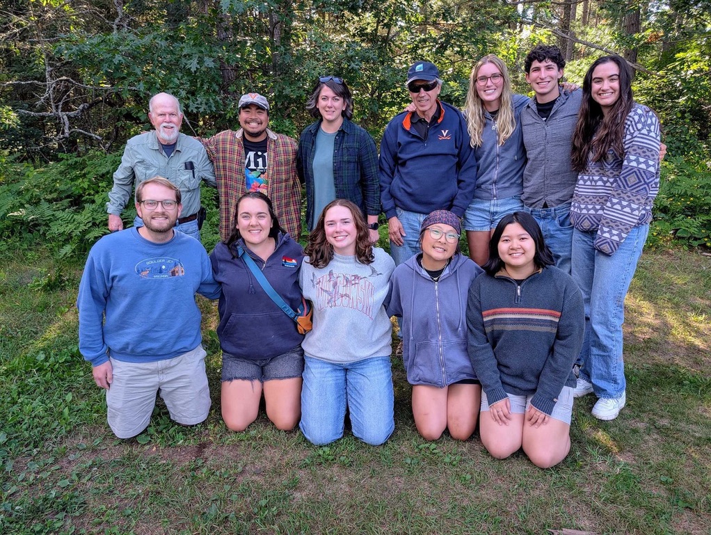 A group of people poses for a picture in the woods. 