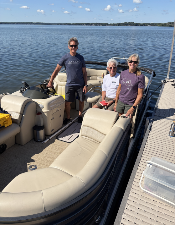 Three people on a boat on a lake with sampling equipment.