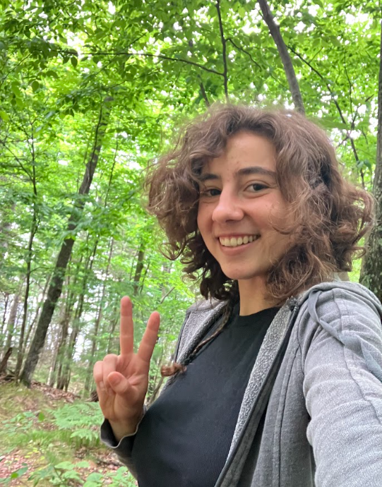 A person poses for a selfie in a forest setting.